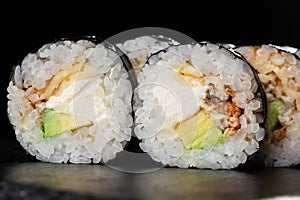 Sushi Rolls with eel, avocado, omelet and Cream Cheese inside. Maki Futomaki Sushi Rolls with eel on black background. Sushi menu