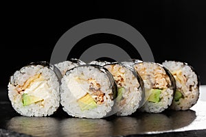 Sushi Rolls with eel, avocado, omelet and Cream Cheese inside. Maki Futomaki Sushi Rolls with eel on black background. Sushi menu