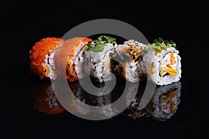 Sushi rolls isolated on  black background, food reflection in  glass, japanese food, set with salmon, vegetables, flying fish