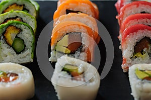 sushi rolls of red tuna, salmon, avocado and butter fish on slate dish. japanese food