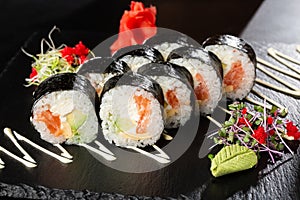 Sushi Rolls with salmon, avocado, omelet and Cream Cheese inside. Maki Futomaki Sushi Rolls with salmon on black background. Sushi