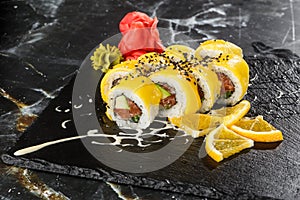 Sushi Rolls with salmon, avocado, omelet inside and mango on top. Sushi Rolls with salmon on black marble background. Sushi menu.