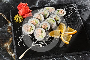 Sushi Rolls with salmon, avocado, tuna and cucumber inside. Maki Futomaki Sushi Rolls with salmon on black marble background .