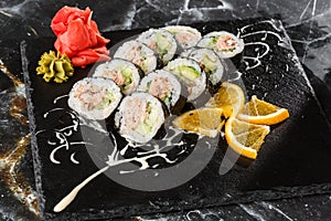 Sushi Rolls with salmon, avocado, tuna and cucumber inside. Maki Futomaki Sushi Rolls with salmon on black marble background .