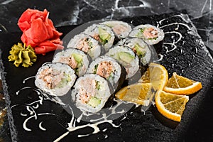 Sushi Rolls with salmon, avocado, tuna and cucumber inside. Maki Futomaki Sushi Rolls with salmon on black marble background .