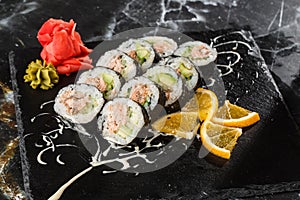 Sushi Rolls with salmon, avocado, tuna and cucumber inside. Maki Futomaki Sushi Rolls with salmon on black marble background .