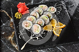 Sushi Rolls with salmon, avocado, tuna and cucumber inside. Maki Futomaki Sushi Rolls with salmon on black marble background .