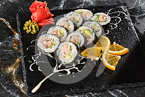 Sushi Rolls with salmon, avocado, tuna and cucumber inside. Maki Futomaki Sushi Rolls with salmon on black marble background .