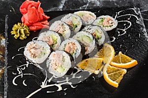 Sushi Rolls with salmon, avocado, tuna and cucumber inside. Maki Futomaki Sushi Rolls with salmon on black marble background .