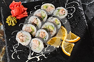 Sushi Rolls with salmon, avocado, tuna and cucumber inside. Maki Futomaki Sushi Rolls with salmon on black marble background .