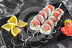 Sushi Rolls with salmon, avocado, tuna and cucumber inside. Maki Futomaki Sushi Rolls with salmon on black marble background .