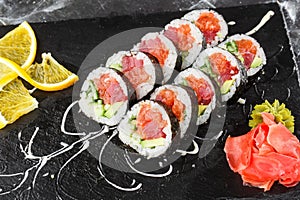 Sushi Rolls with salmon, avocado, tuna and cucumber inside. Maki Futomaki Sushi Rolls with salmon on black marble background .