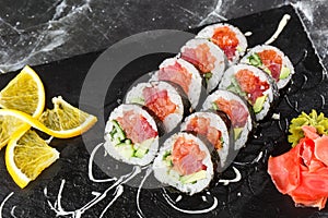 Sushi Rolls with salmon, avocado, tuna and cucumber inside. Maki Futomaki Sushi Rolls with salmon on black marble background .