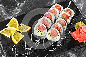 Sushi Rolls with salmon, avocado, tuna and cucumber inside. Maki Futomaki Sushi Rolls with salmon on black marble background .