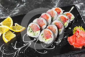 Sushi Rolls with salmon, avocado, tuna and cucumber inside. Maki Futomaki Sushi Rolls with salmon on black marble background .