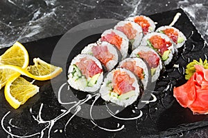 Sushi Rolls with salmon, avocado, tuna and cucumber inside. Maki Futomaki Sushi Rolls with salmon on black marble background .