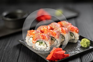 Sushi rolls with salmon, caviar, cucumber and cream cheese on a black plate on a dark background. Japanese food. Sushi