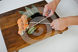 Sushi rolls with salmon and chopsticks on wooden table, closeup