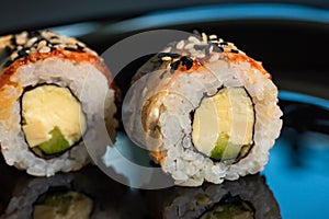 Sushi rolls with sesame seeds on a dark background close-up. Japanese food