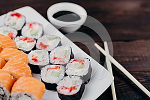 Sushi rolls set on plate with sauce and chopsticks