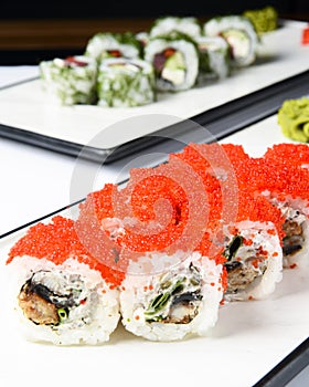 Sushi rolls set with red caviar and cream cheese served on a white plate over white background.