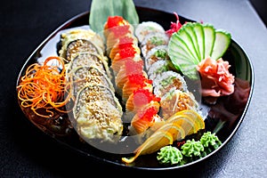 Sushi rolls set served on glass plate on dark background