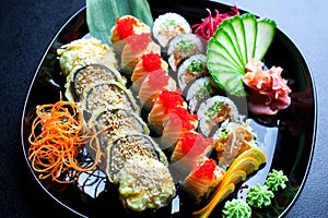 Sushi rolls set served on glass plate on dark background