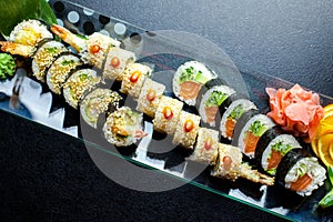Sushi rolls set served on glass plate on dark background
