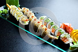 Sushi rolls set served on glass plate on dark background