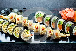 Sushi rolls set served on glass plate on dark background