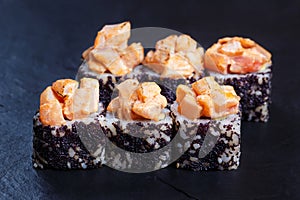 Sushi rolls topped with torched salmon and black caviar served