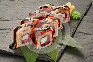 sushi rolls with tuna salmon eel unagi and avocado on a black stone plate.