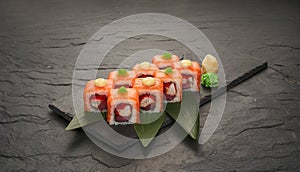 sushi rolls with tuna salmon eel unagi and avocado on a black stone plate.