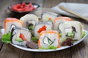 Sushi rolls on a white plate with ginger and a kitchen napkin in the background