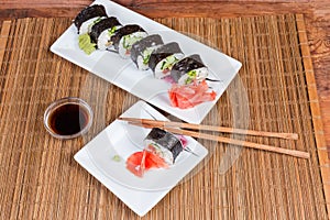 Top view of sushi on rectangular plates, condiments, chopsticks