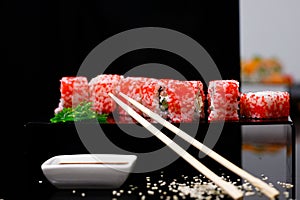 Sushi with salmon. Soy sauce, red caviar. Sushi on a black background.