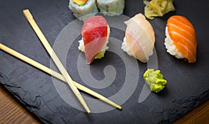 Sushi and Sashimi rolls on a black stone slatter. Fresh made Sushi set with salmon, prawns, wasabi and ginger. Traditional Japanes