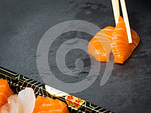 Sushi and Sashimi rolls on a black stone slatter. Fresh made Sushi set with salmon, prawns, wasabi and ginger. Traditional Japanes