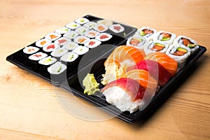 Sushi and Sashimi rolls on a wooden table. Fresh made Sushi set with salmon, prawns, wasabi and ginger. Traditional Japanese cuisi