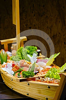 Sushi sashimi set in a wooden boat on a brown