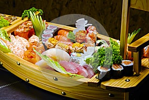 Sushi sashimi set in a wooden boat on a brown