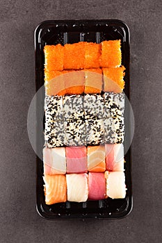 Sushi set compositionally located on a dark surface.