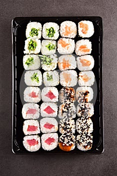 Sushi set compositionally located on a dark surface.