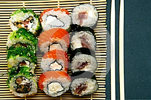 Sushi set with different maki - hosomaki, futomaki and uramaki on bamboo mate with chopsticks