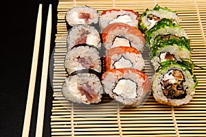 Sushi set with different maki - hosomaki, futomaki and uramaki on bamboo mate with chopsticks