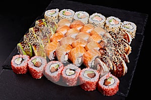 Sushi set of different rolls with different fillings on a slate of black stone