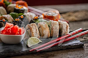 Sushi set food photo. Rolls served on brown wooden and slate plate. Close up of sushi