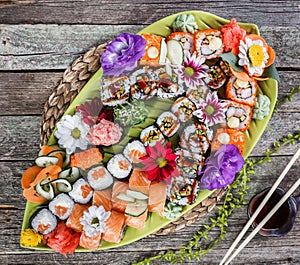 Sushi Set nigiri and sushi rolls decorated with flowers on bamboo background. Japanese cuisine.