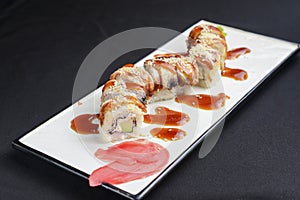 Sushi set, sushi rolls with cream cheese and eel served on a white plate over black background
