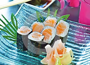 Sushi set. Salmon maki rolls and pickled ginger on a blue, glass plate. Japanese delicacy.
